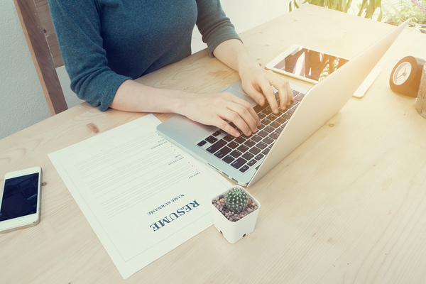 Woman working at a desk typing on a laptop.