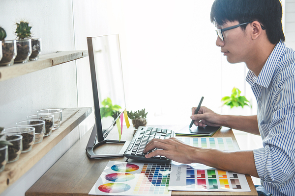 Graphic designer working on a desktop computer with a stylus.