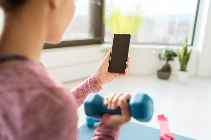 Woman looking at her phone while lifting weights.