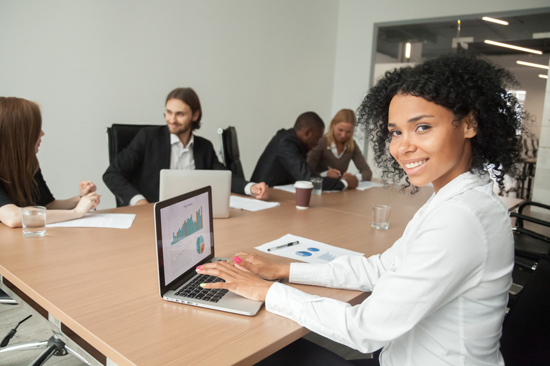 Woman sitting at a conference table smiling.