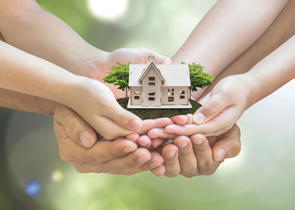Hands holding a miniature home.