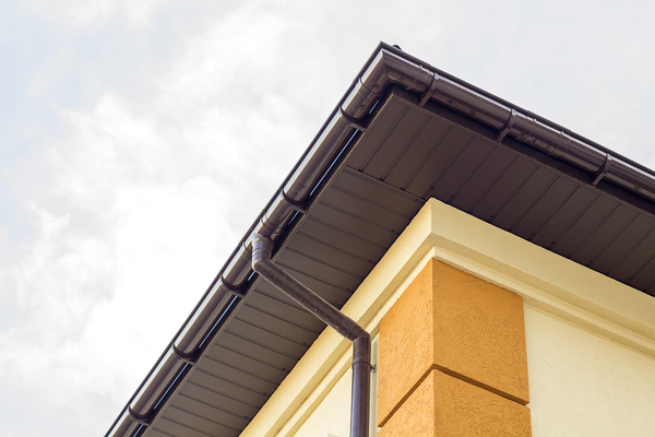 Corner of a house with brown gutters and down spout.