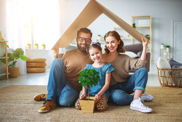 Family creating the shape of a house using a piece of cardboard as the roof.