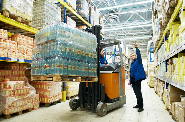 Warehouse workers moving pallets of food with a lift.