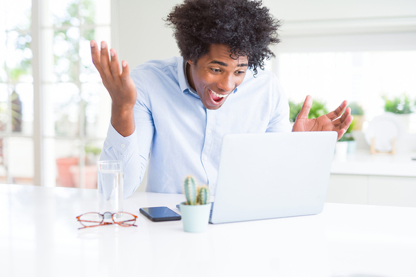 Man appearing surprised while looking at his laptop.