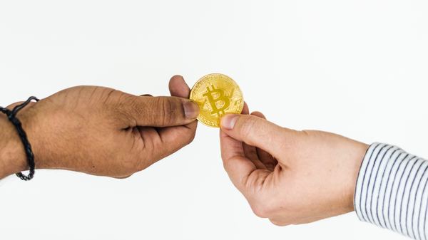 Two people holding a gold bitcoin coin.