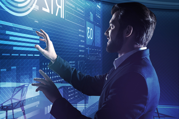 Man in a business suit looking at a large screen with data.