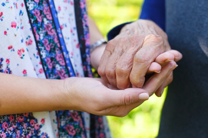 Caregiver holding the hand of an elderly person.