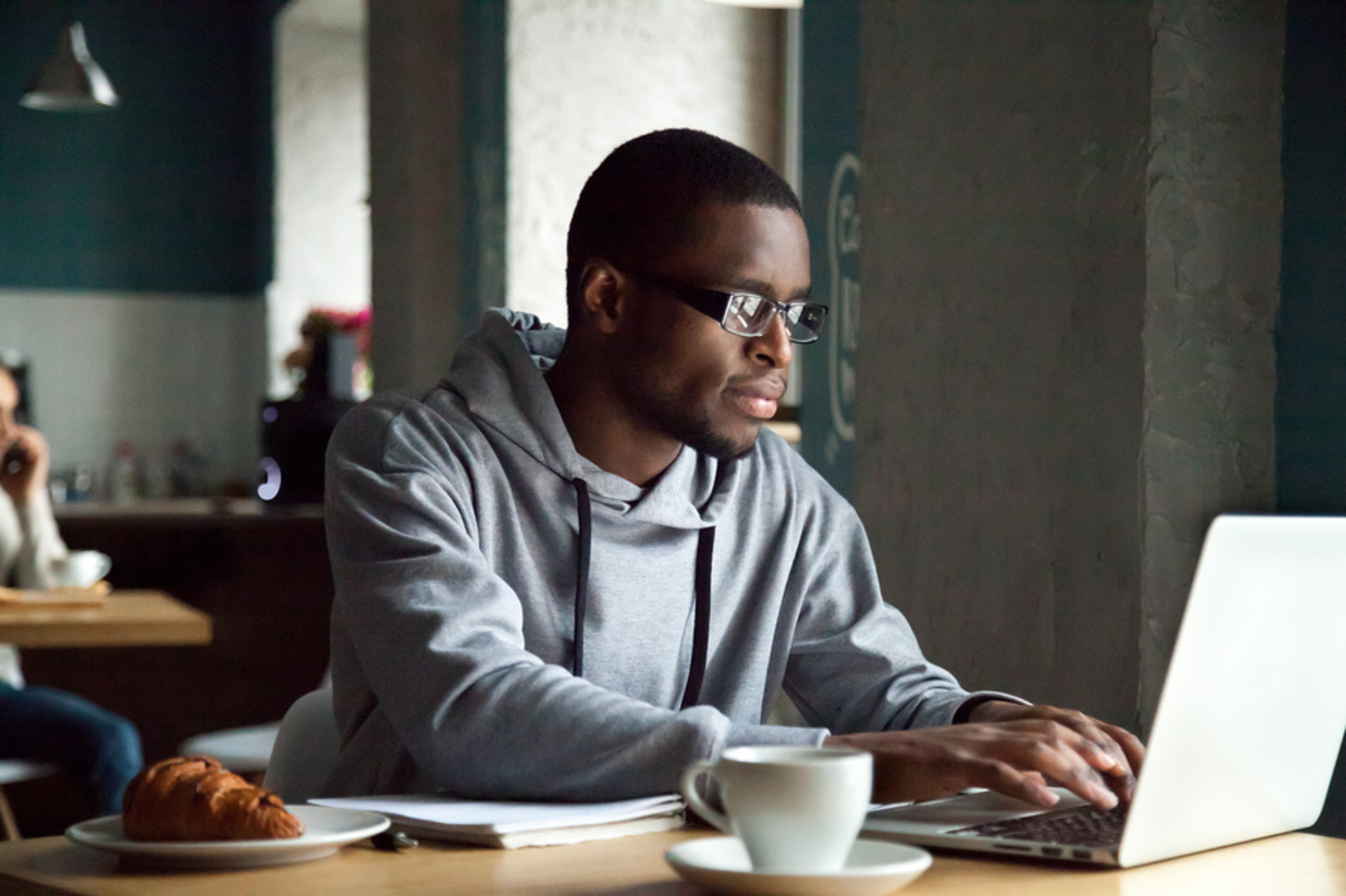 Man sitting at a table typing on a laptop.