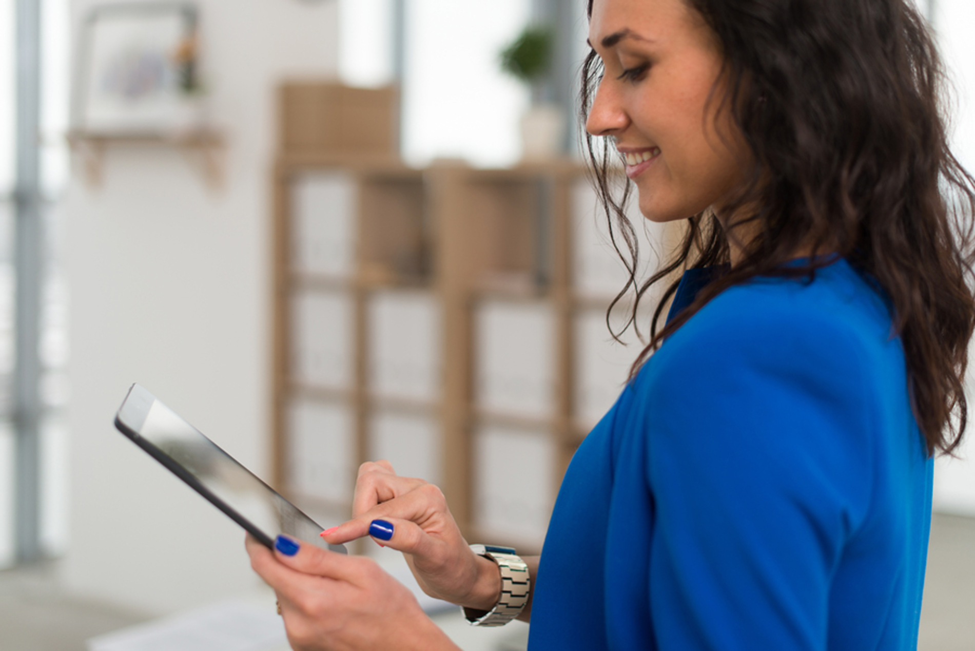 Woman smiling while typing on her tablet.