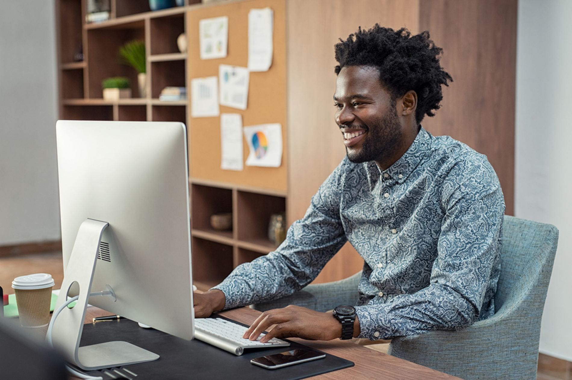 Man sitting in front of his desktop computer smiling.