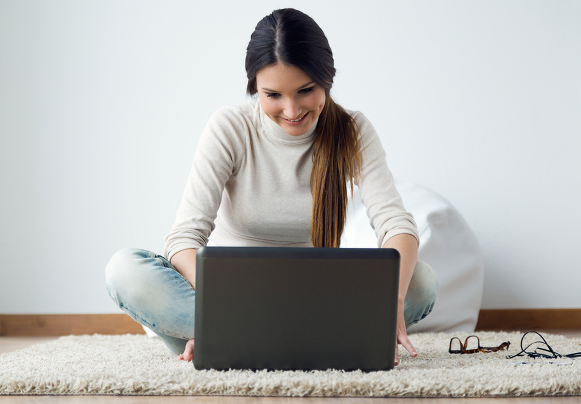 Woman sitting on the floor in front of her laptop.