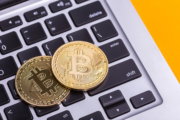 Two gold bitcoin coins on top of a laptop keyboard.