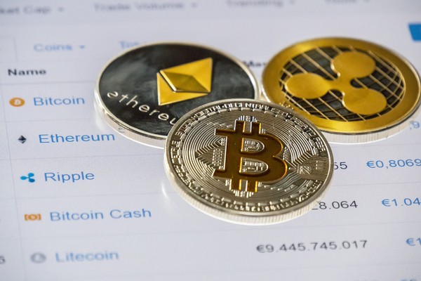 Gold and silver coins with bitcoin symbol, ripple symbol and ethereum symbol.