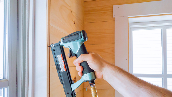 Person using a nail gun to install windows.