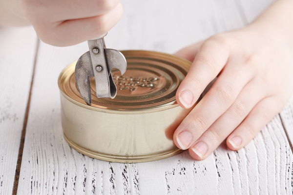 Person opening a can with a can opener.