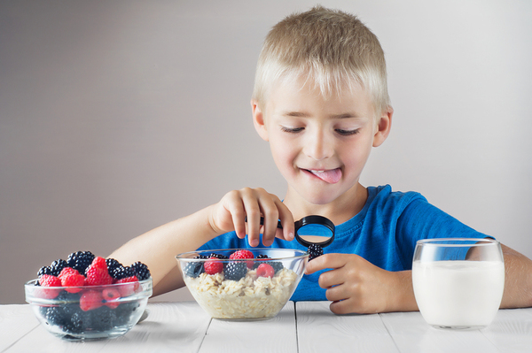 Young boy looking at a blackberry with a magnifying glass.