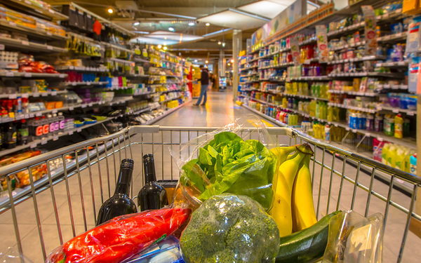 Person pushing a shopping cart filled with groceries.