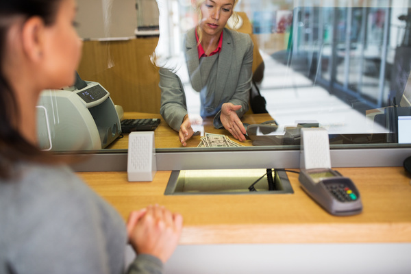 Woman receiving cash from a bank teller - financial services