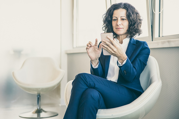 Customer Engagement image of a woman sitting in a chair looking at her phone screen.