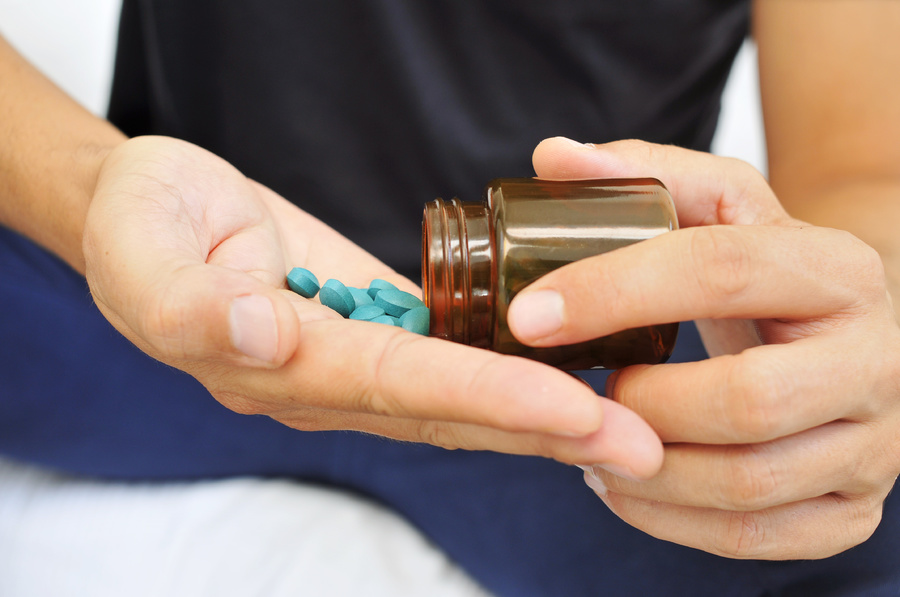 Pouring blue pills into a palm.