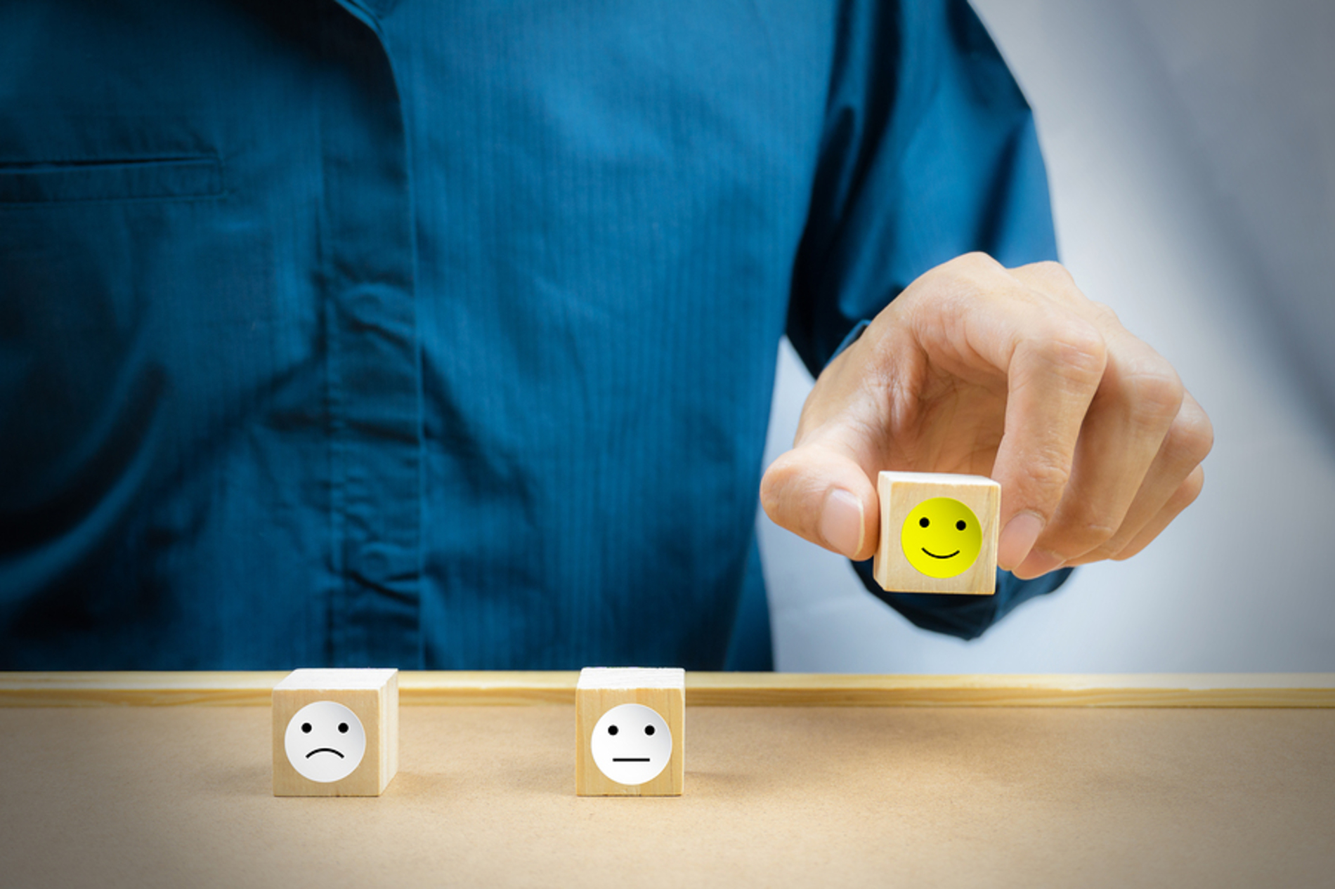 Wood blocks with frown face, happy face and expressionless face.