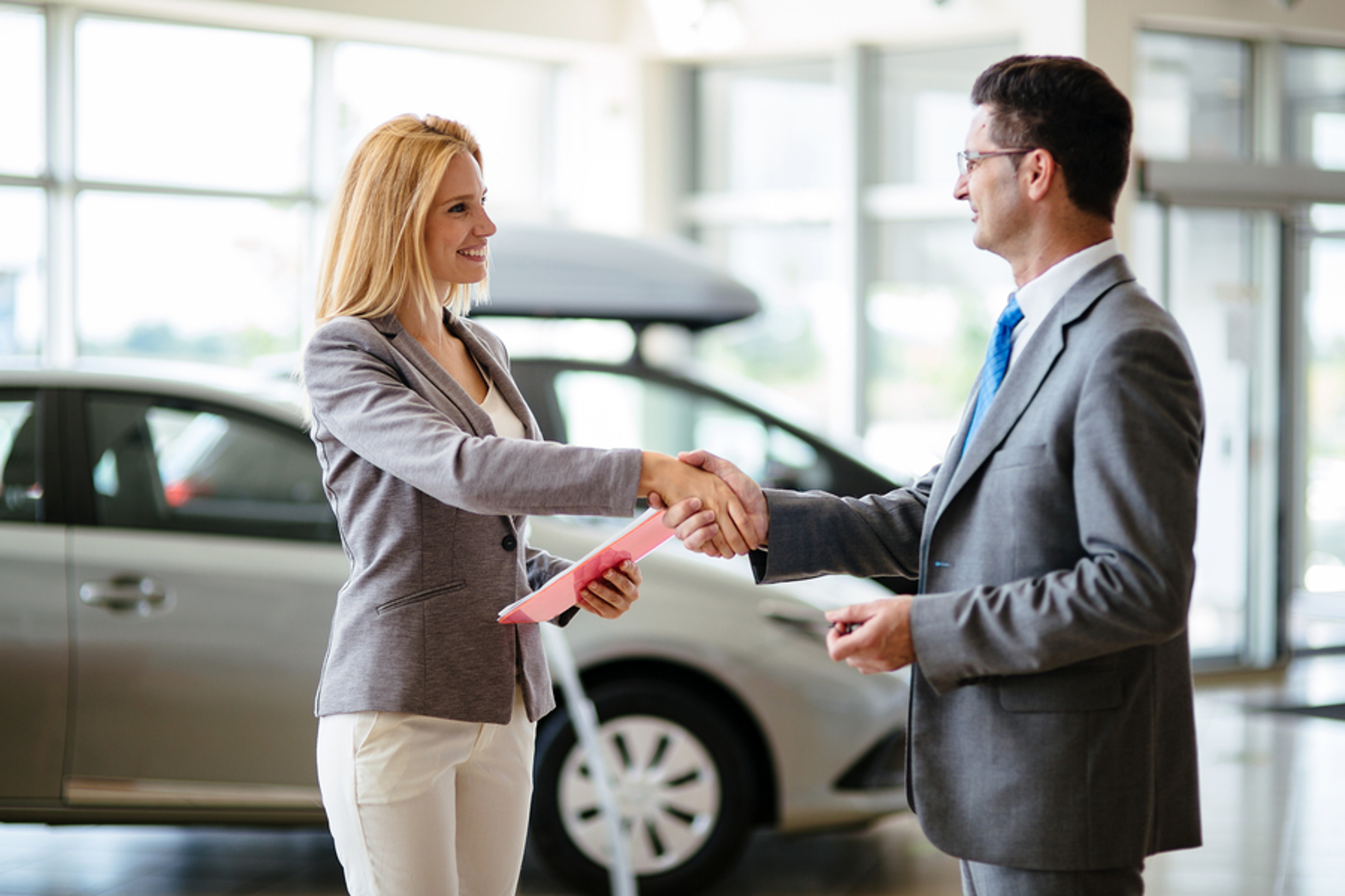 Woman shaking hands with a car salesman.