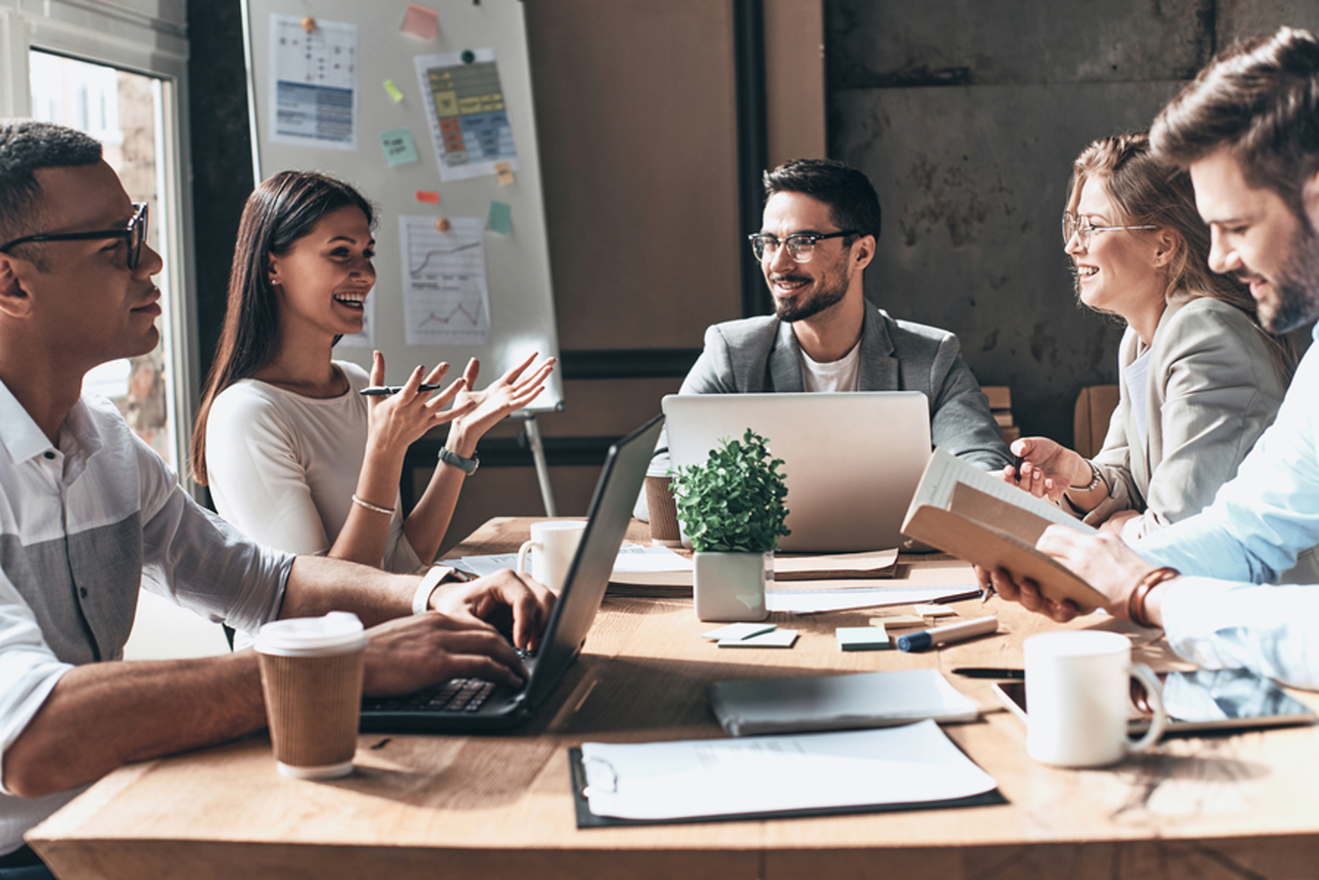 Group of colleagues working around a table together smiling.