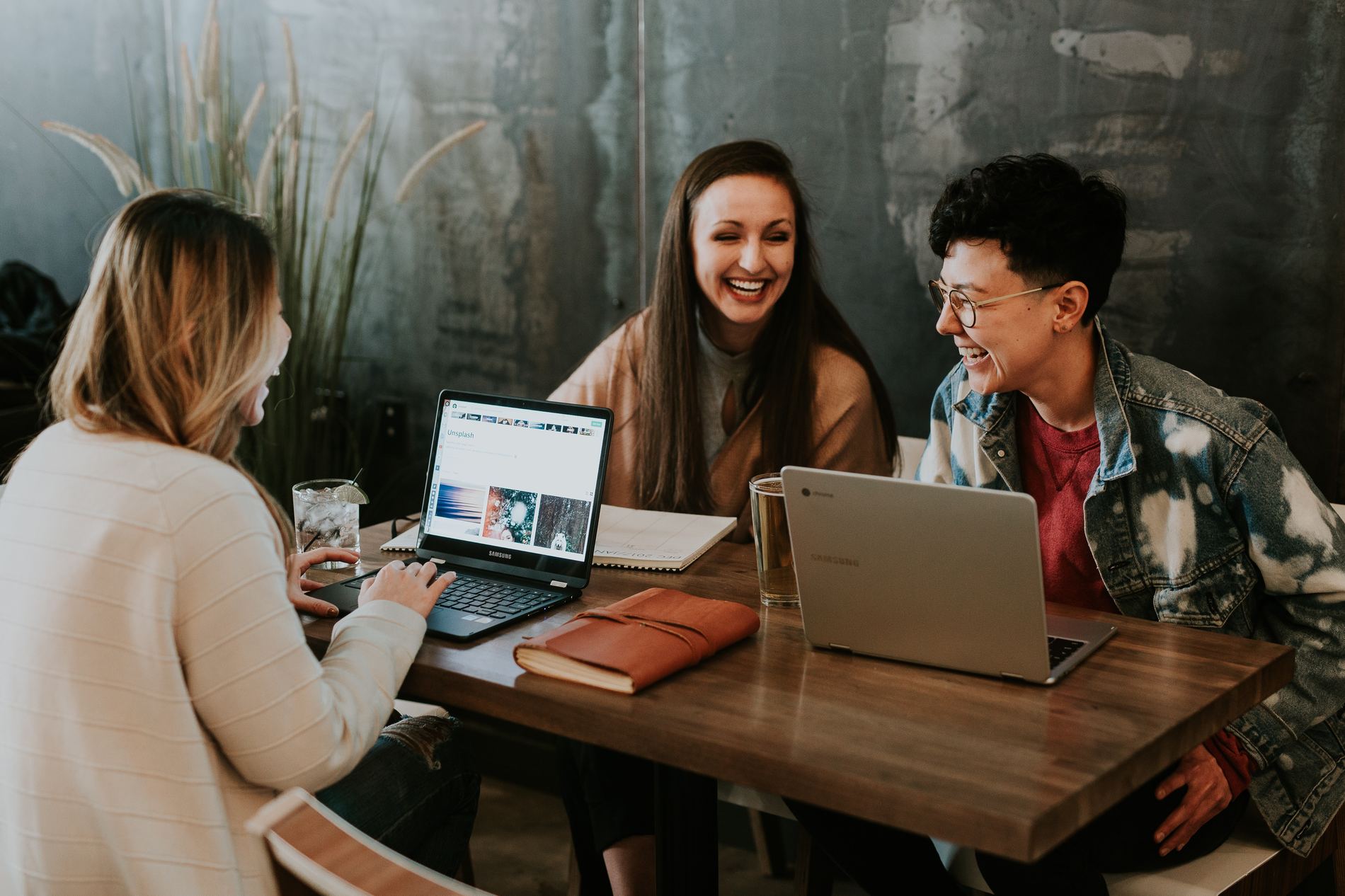 Three people working at a table together with laptops.