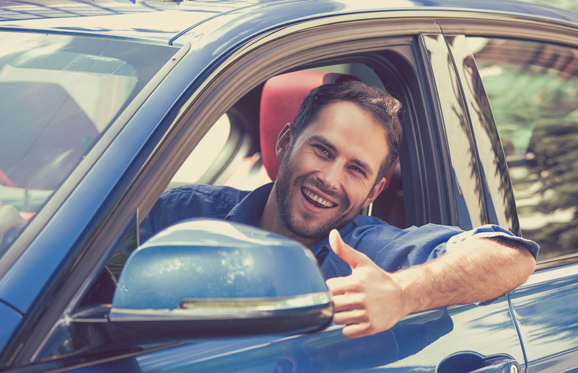 Man smiling while sitting in his car.