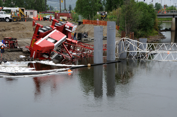 Crane on its side partly in a body of water.