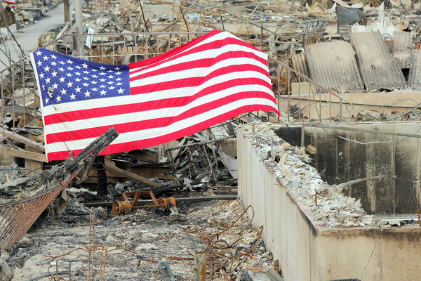 American flag across a destroyed building foundation.