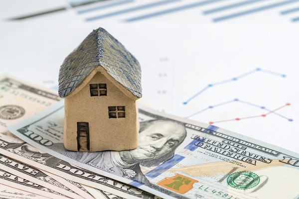 US paper money and a small model of a house.