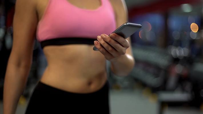 Woman in a gym looking at her phone.