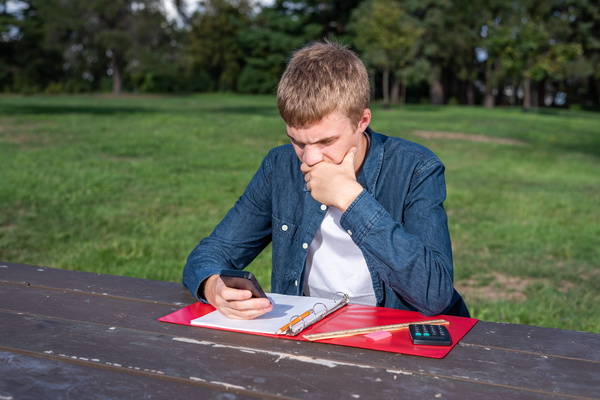 Looking at a phone outside on a picnic table.