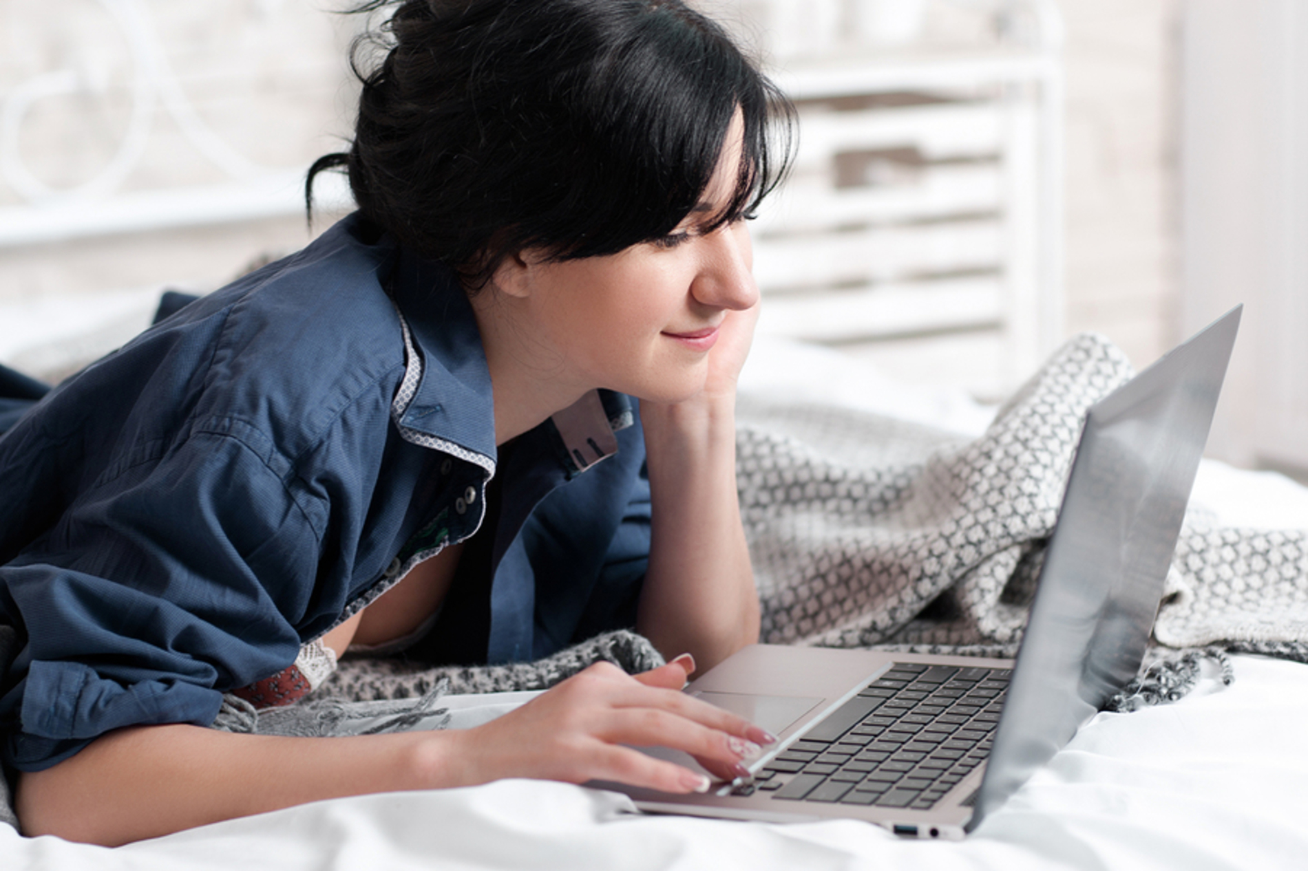 Woman lying on her bed using her laptop.