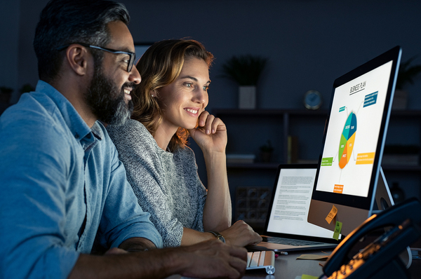 Two colleagues looking at a desktop screen with graphical data. business value of big data