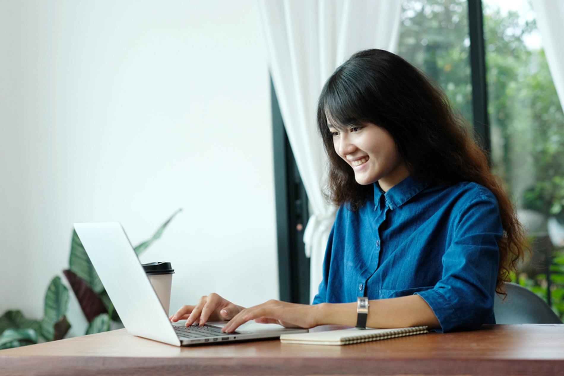 Happy woman typing on a laptop computer.