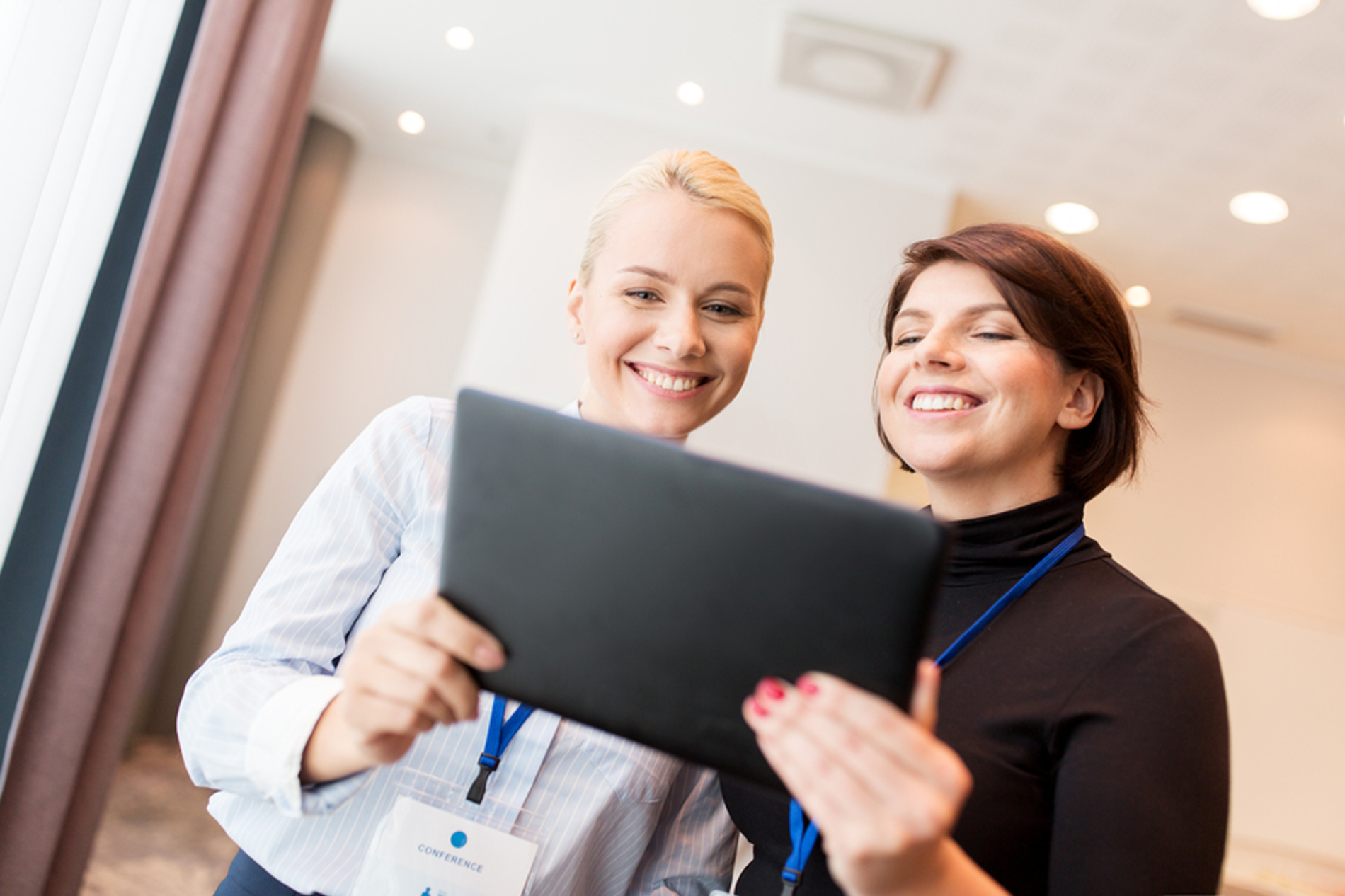 Two smiling women looking at a tablet together. Two smiling women looking at a tablet together.