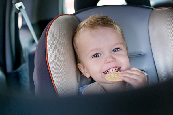 Child in a car seat eating a cracker.