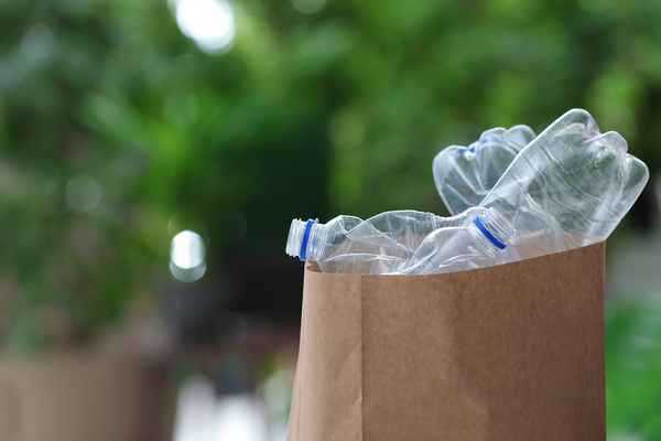 Paper bag filled with empty plastic bottles.