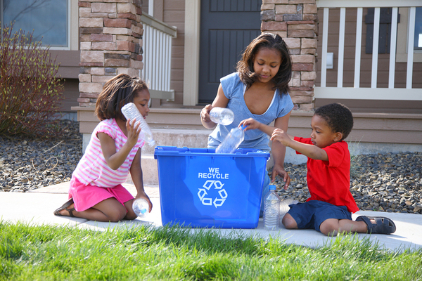 Family placing plastic bottles in a recycling bin.