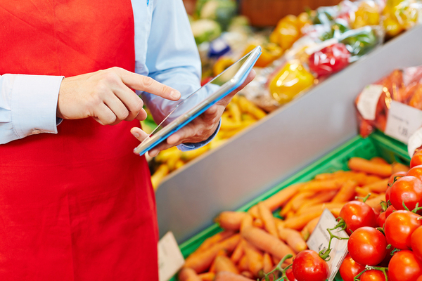 Person in a grocery store looking at a tablet.