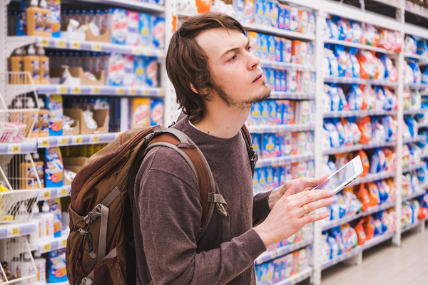 Person shopping in a grocery store referring to a tablet.