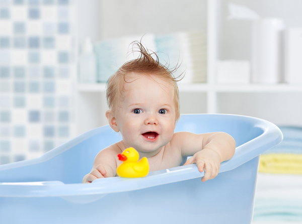 Baby in a bathtub with a yellow rubber ducky.