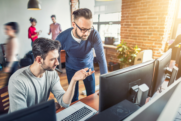 Two colleagues looking at a desktop computer screen. mainframe optimization