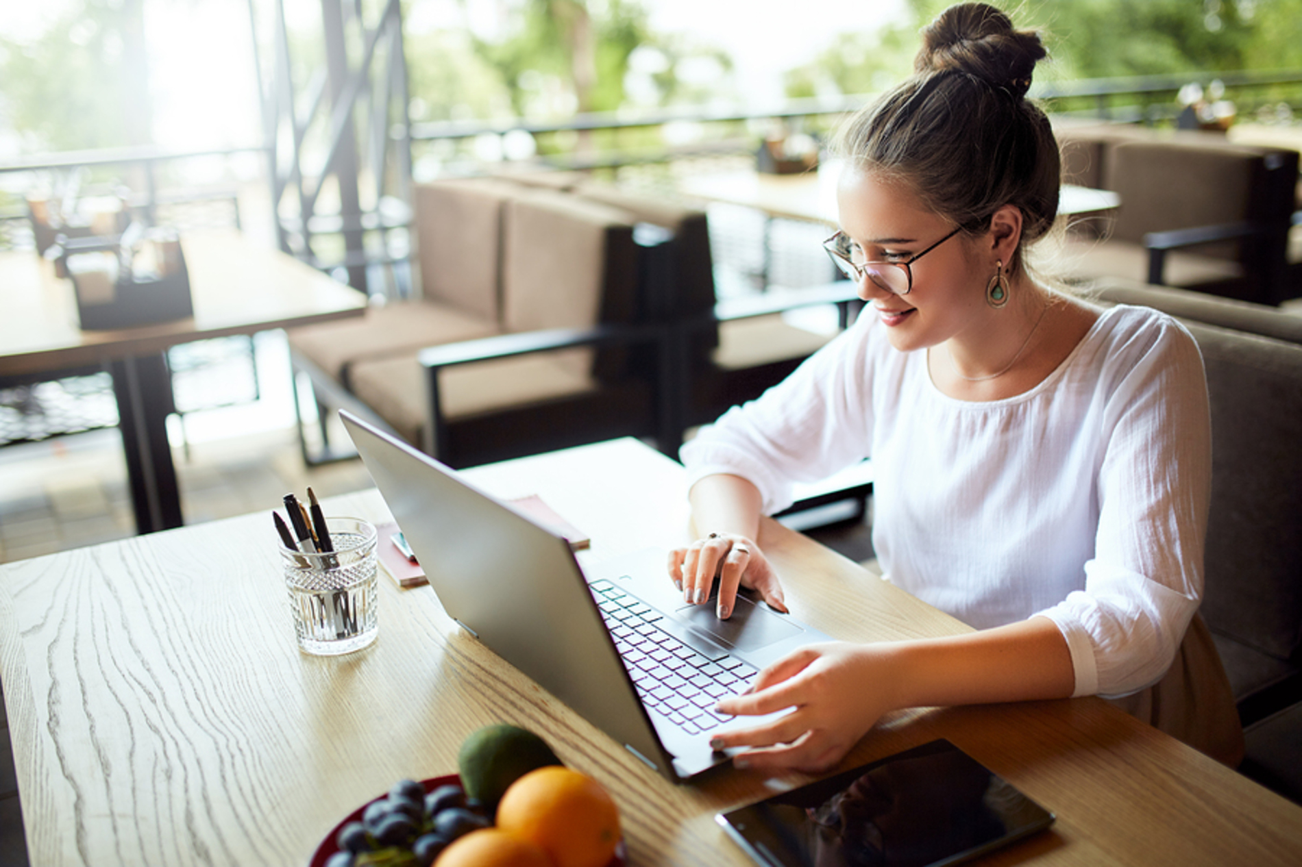 Happy young adult woman typing on a laptop.