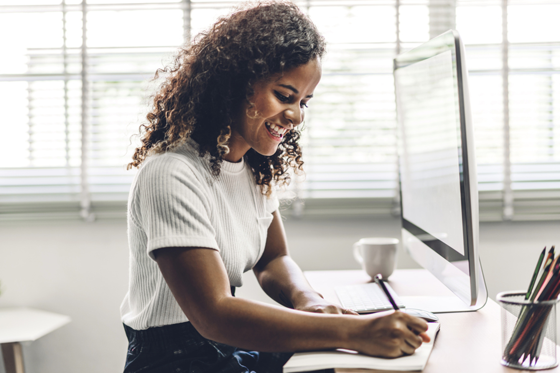 Woman sitting at her desk writing in a notebook.