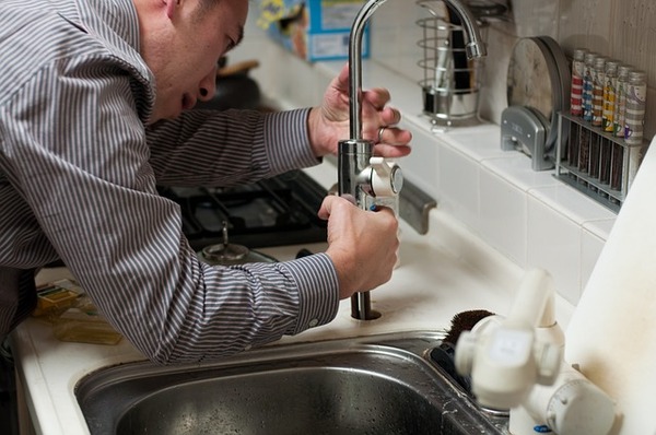 Plumber repairing a faucet on a sink.