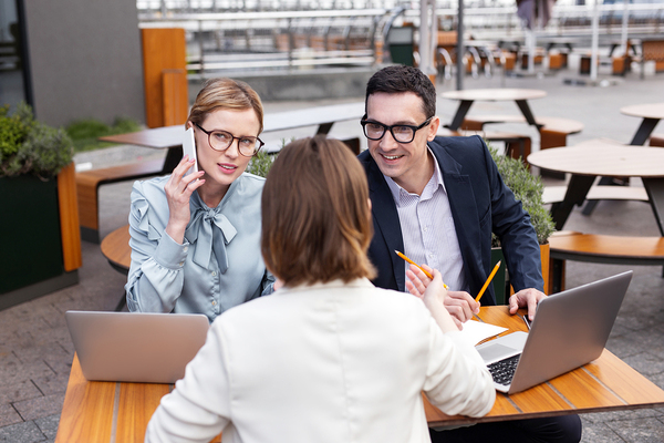 Group of three people sitting at a table working with laptops.